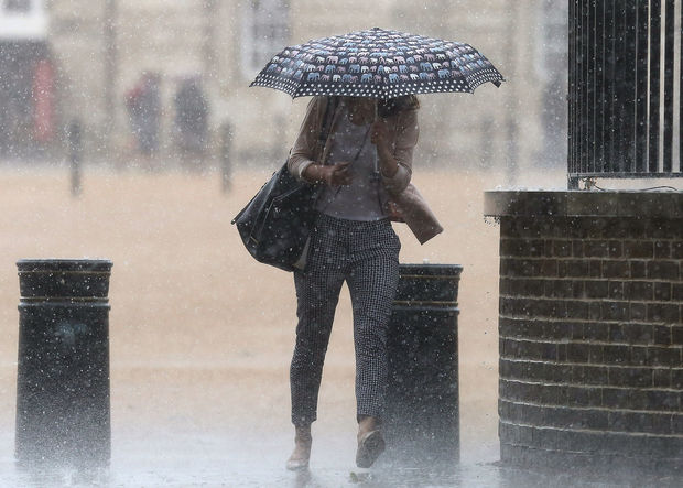 A woman walks through the rain off Horse Guards Parade in Westminster, London.