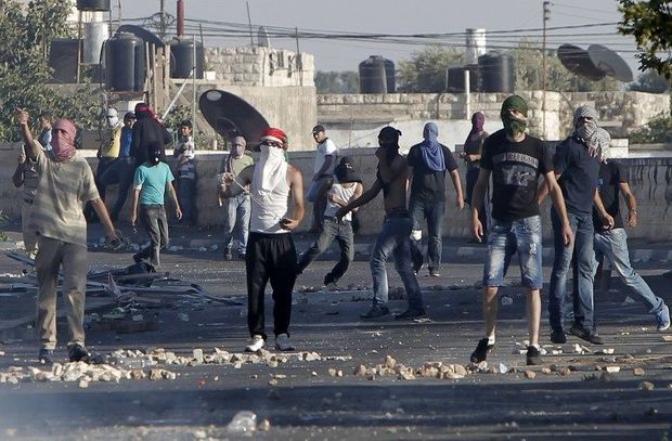 Palestinian protesters throw stones towards Israeli forces (unseen) during clashes in Shuafat, East Jerusalem on July 4, 2014. Before and after the funeral of a Palestinian teenager believed murdered by Israelis, Palestinians clashed with Israeli police near the procession and elsewhere in east Jerusalem, and thousands of officers were deployed in case of widespread unrest.   AFP PHOTO /AHMAD GHARABLI
