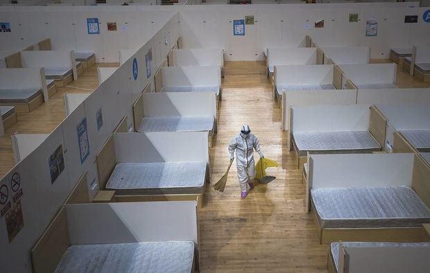 In this March 8, 2020, photo released by Xinhua News Agency, a staff member clean up an empty makeshift hospital in Wuhan, central China's Hubei Province. The makeshift hospital converted from a sports venue was officially closed on Sunday after its last batch of cured COVID-19 patients were discharged. (Xiao Yijiu/Xinhua via AP)