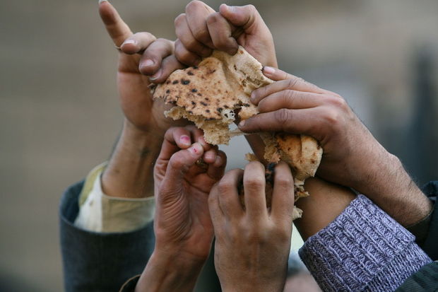 Egyptian protesters share a loaf of bread while chanting anti government and anti President Hosni Mubarak slogans during a demonstration in front of an ancient mosque to protest high prices and government carelessness, in Cairo, Egypt Thursday, Jan. 18, 2007. (AP Photo/Nasser Nasser)