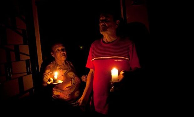 Pedro Martínez (der), de 73 años, y su esposa Aura, de 60, iluminan su casa con velas durante un apagón en Valencia, Venezuela, el 8 de abril del 2013.Los apagones, la violencia, la inflación, la corrupción oficial y la escasez de alimentos son factores que podrían incidir en las elecciones presidenciales del domingo. (AP Photo/Ramon Espinosa)